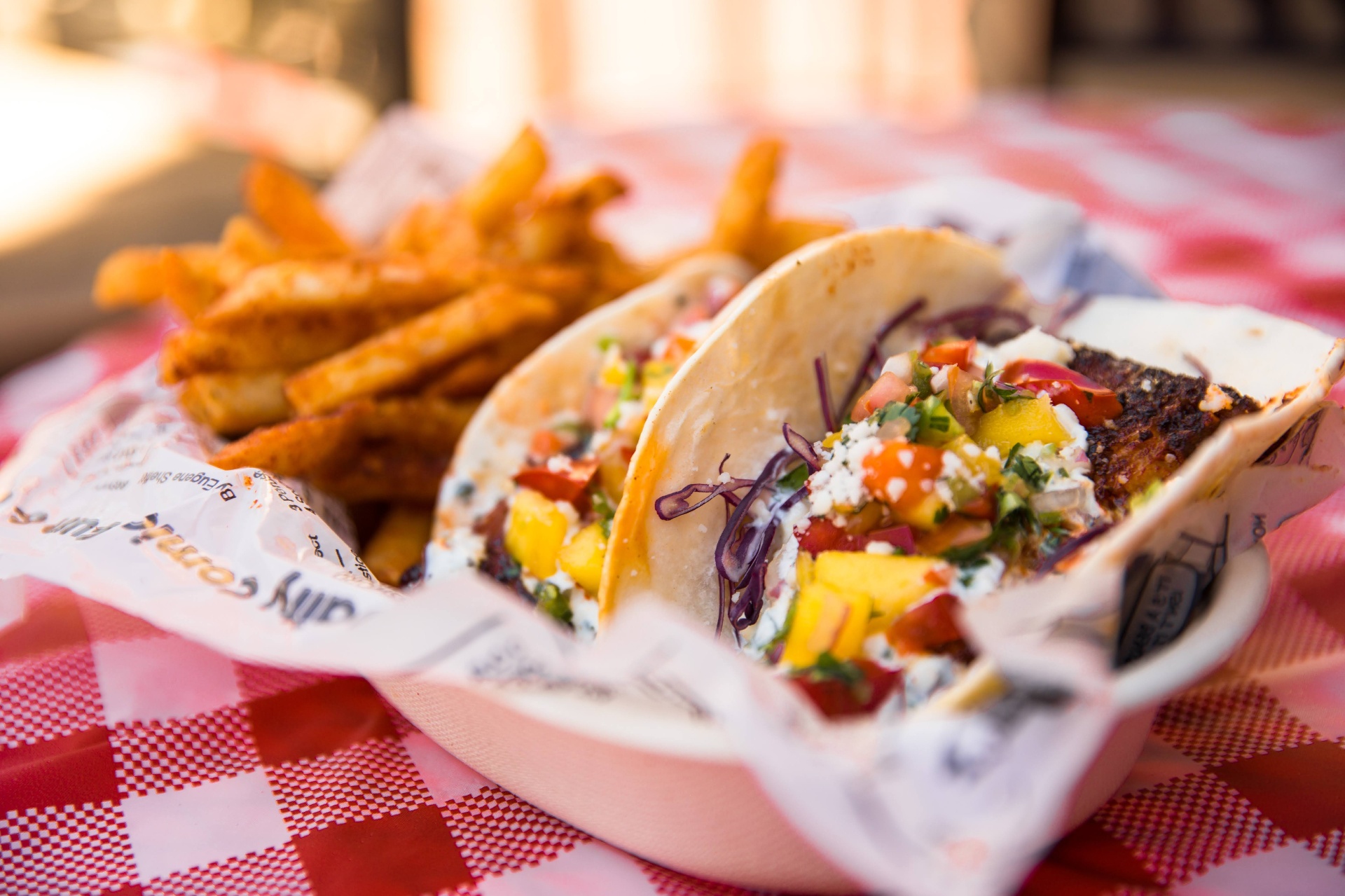 Two blackened fish tacos with mango pico on a red checkered cloth