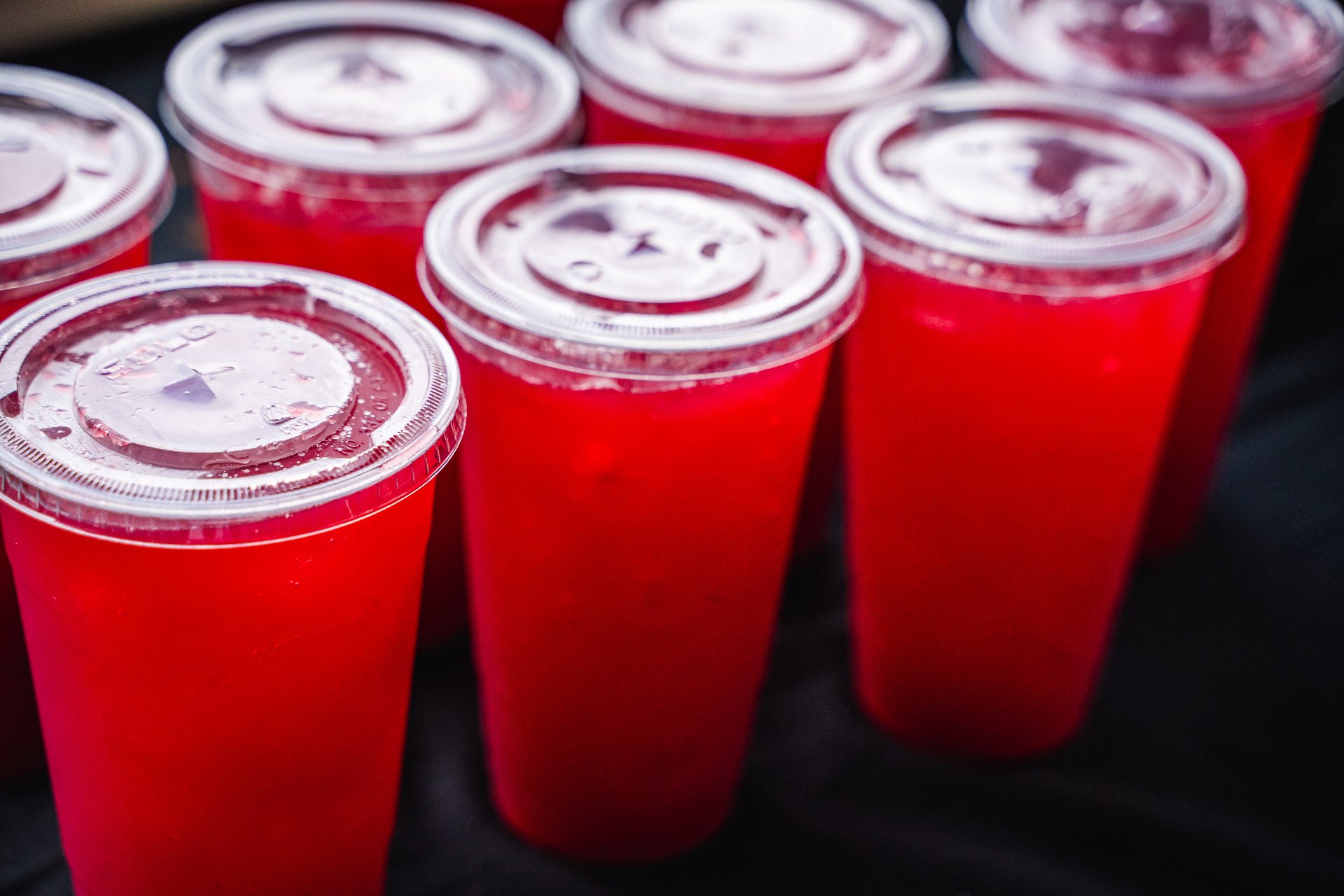 Cups of bright red homemade blackberry lemonade lined up