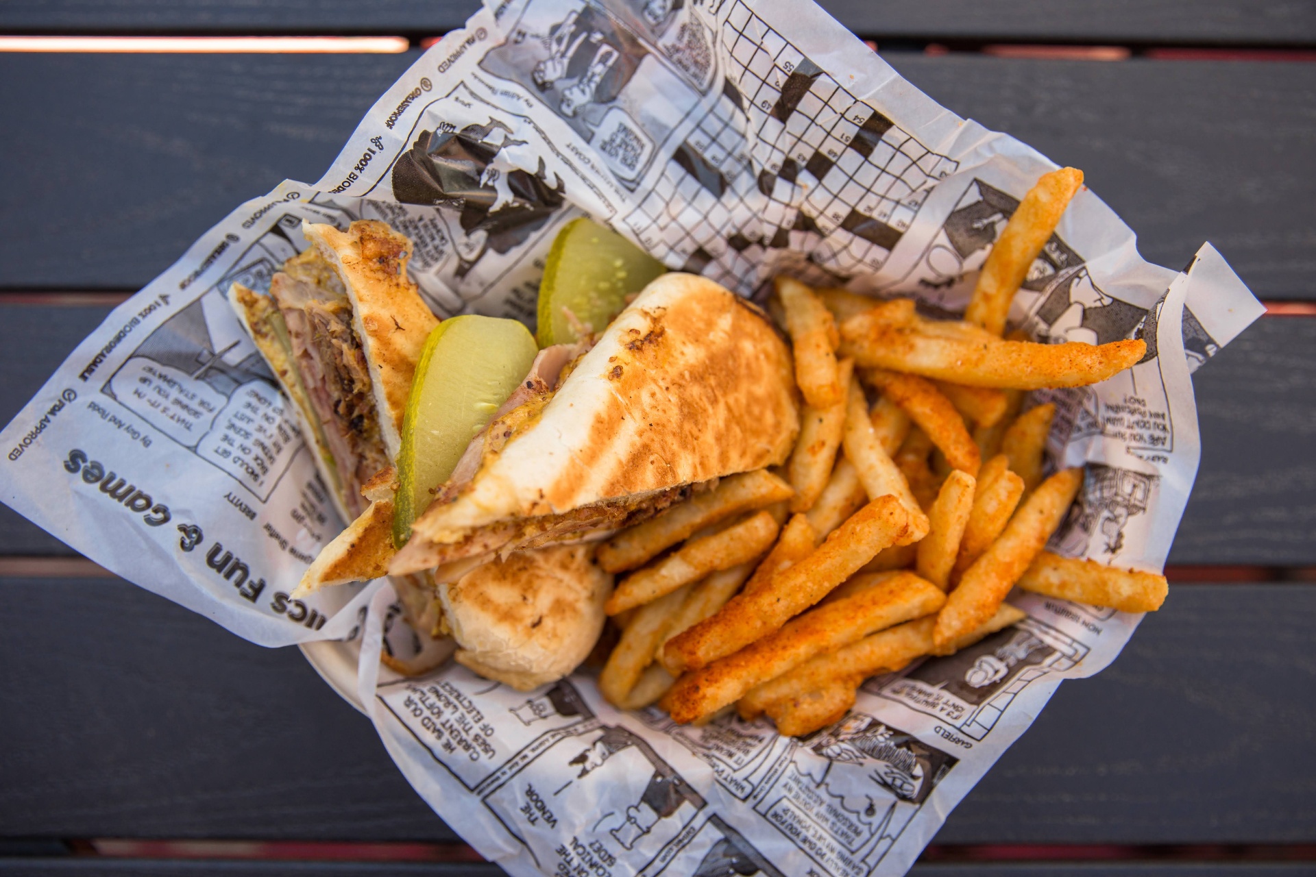 Cajun Cubano sandwich with seasoned fries in a comic-print basket