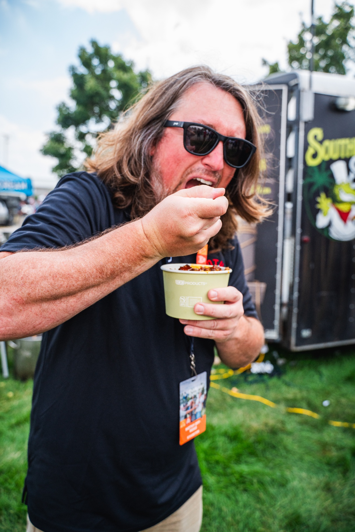 Guest digging into a cup of Southern Soul food in front of the trailer