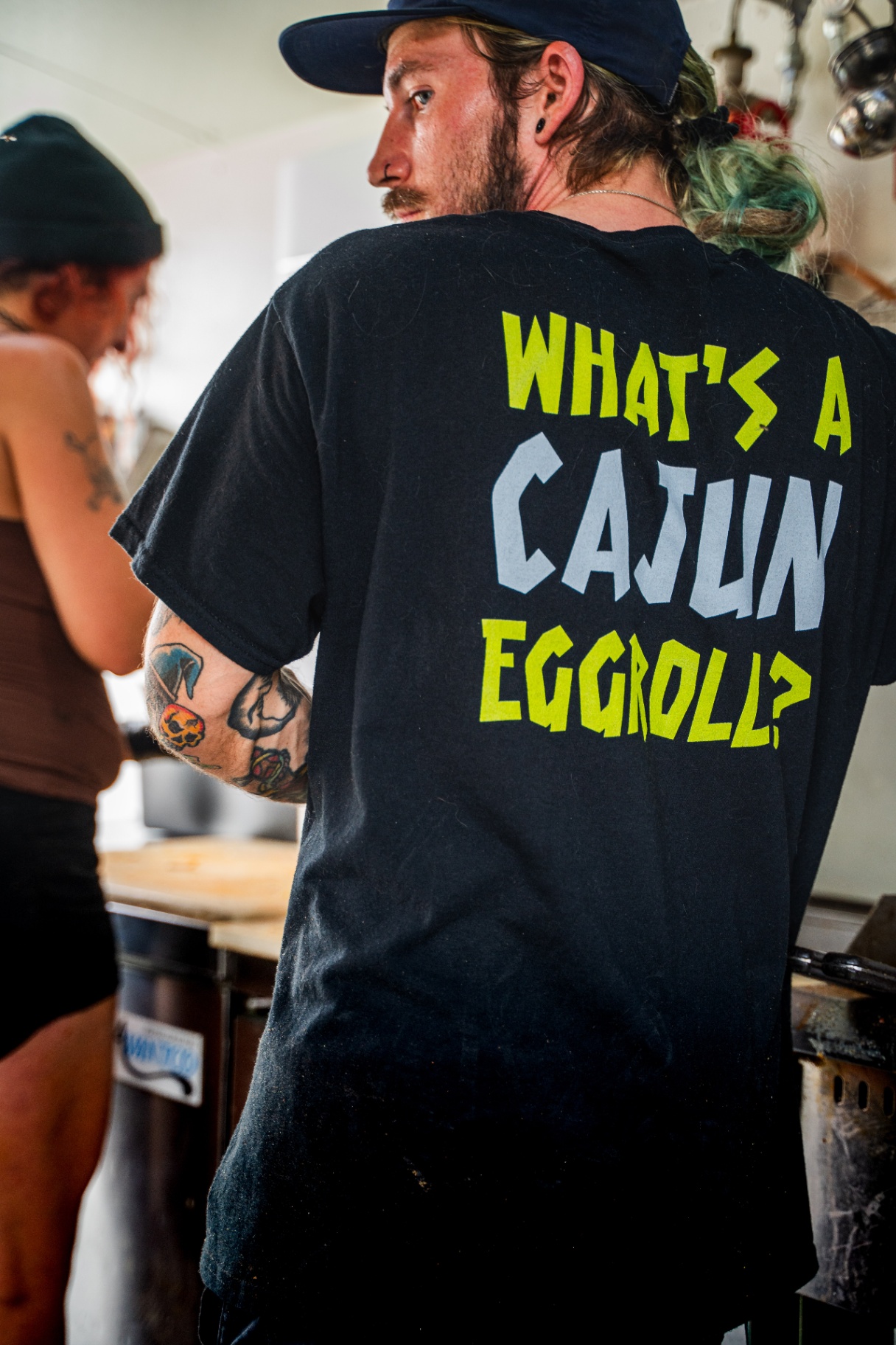 Crew member in a 'What's a Cajun Eggroll?' shirt working the line